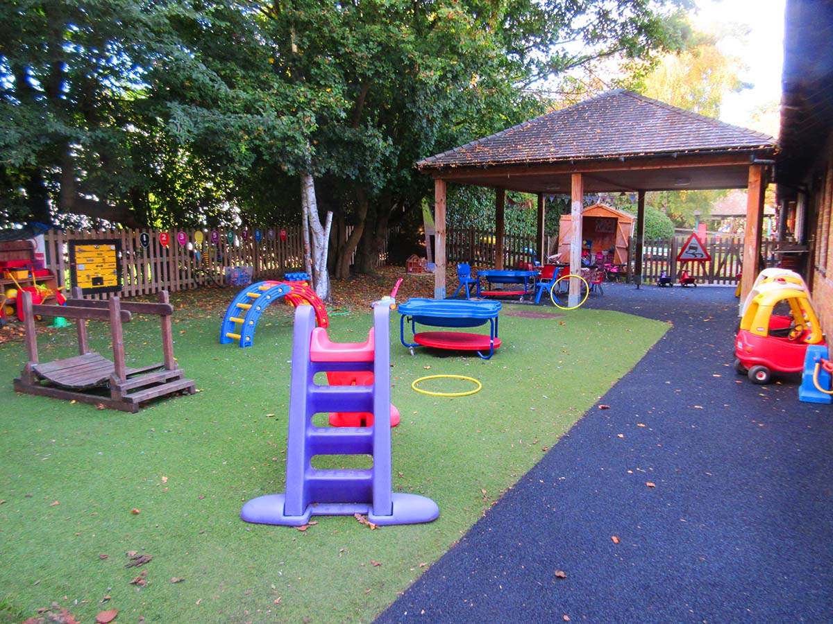 The pre-school outside play area featuring the artificial grassed area and sheltered play area.